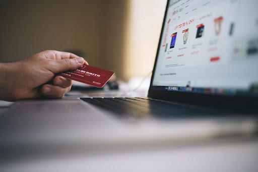 A person holding a credit card in front of a computer screen with the intention to buy an offer