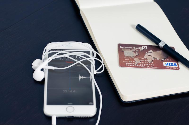 Ipod next to a notepad with a credit card and pen on top